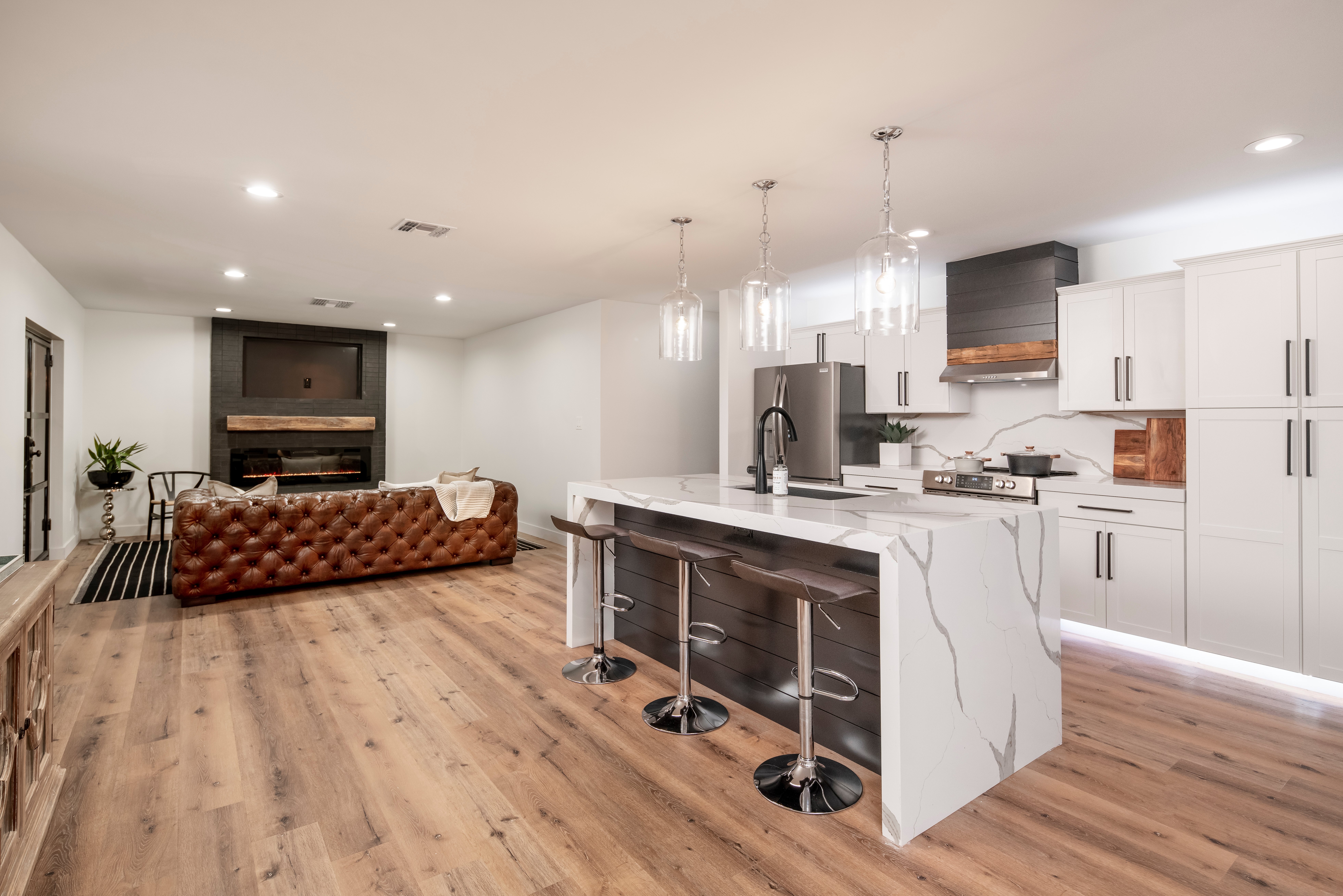 Elegant dining room decorated in whites and greys with a large wood table opens to the Arizona evening, Great room with modern decor, white furnishings, and stainless steel appliances