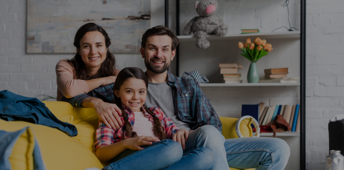 Smiling family in their living room, representing the bright future possible with fast home sales in Phoenix through The District PHX
